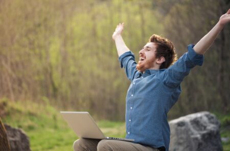 happy-hipster-with-laptop-in-the-forest-76330745