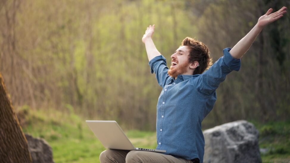 happy-hipster-with-laptop-in-the-forest-76330745